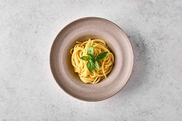 Pasta de espaguetis y albahaca en placa de cerámica sobre fondo claro espacio de copia plana laicos