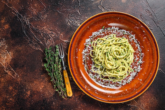 Pasta de espaguetis de espinacas con salsa pesto y parmesano. Fondo oscuro. Vista superior. Copie el espacio.