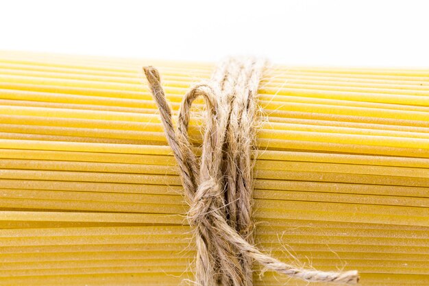 Pasta de espaguetis orgánicos de color amarillo sobre un fondo blanco.