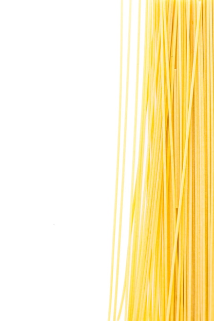 Pasta de espaguetis orgánicos de color amarillo sobre un fondo blanco.