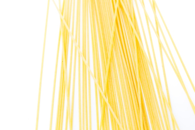 Pasta de espaguetis orgánicos de color amarillo sobre un fondo blanco.