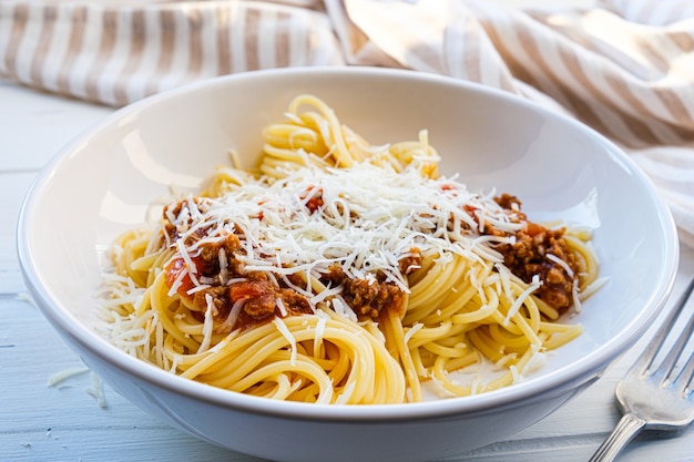 Pasta de espaguetis con salsa de tomate y carne y queso en un plato blanco.