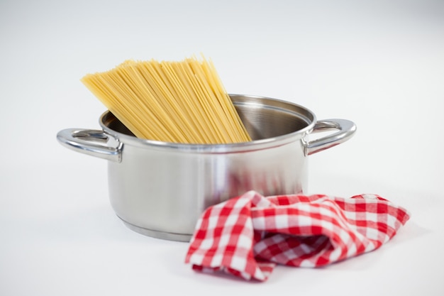 Pasta de espaguetis en utensilio sobre fondo blanco.