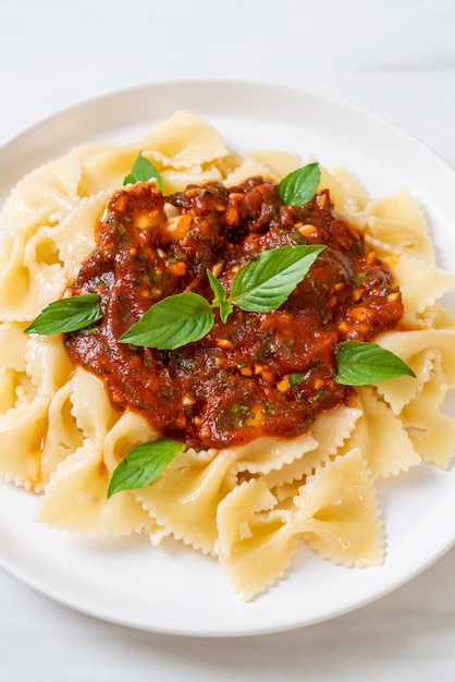 Foto pasta de farfalle con albahaca y ajo en salsa de tomate