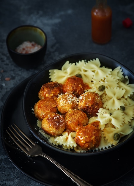 Pasta farfalle con albóndigas de pollo en salsa de tomate