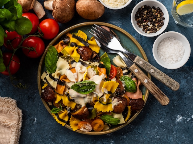 Pasta Farfalle con champiñones, albahaca, tomate y salsa de crema. Cocina tradicional italiana. comida mediterránea