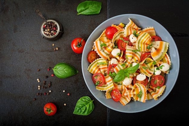 Pasta Farfalle Salat mit Tomaten, Mozzarella und Basilikum.