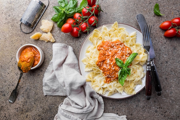 Pasta farfalle con salsa boloñesa de tomate vegetariana casera, queso parmesano y hierbas en un plato