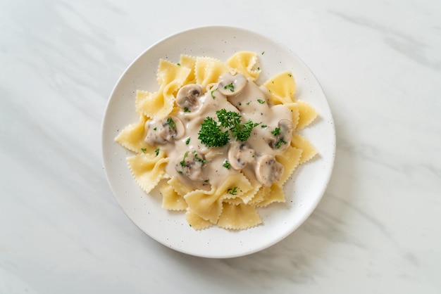 pasta farfalle con salsa de crema blanca de champiñones - estilo de comida italiana