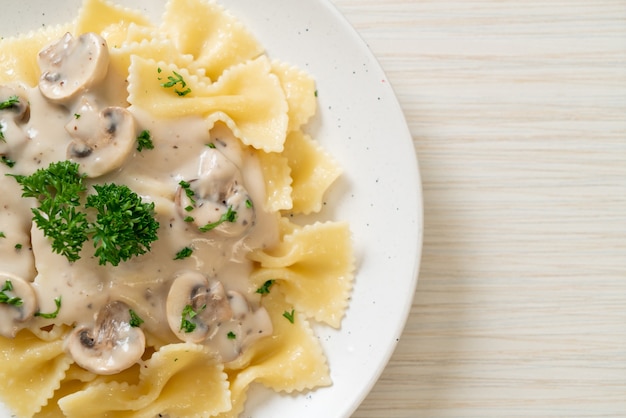 Foto pasta farfalle con salsa de crema blanca de champiñones - estilo de comida italiana