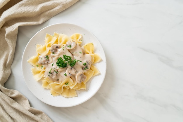 pasta farfalle con salsa de crema blanca de champiñones - estilo de comida italiana