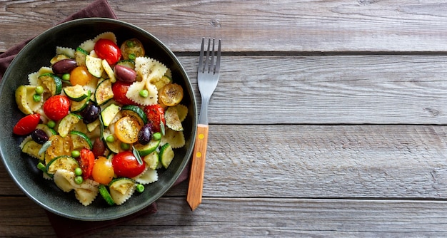 Pasta farfalle con tomate calabacín guisantes aceitunas Kalamata y salvia alimentación saludable comida vegetariana