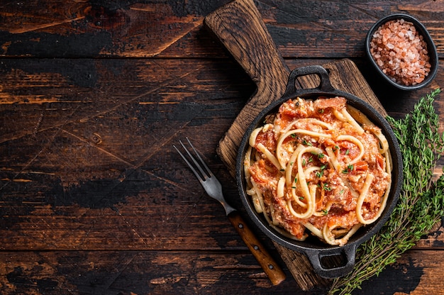 Pasta feta horneada a la moda con tomates asados al horno y queso en una sartén. Fondo de madera oscura. Vista superior. Copie el espacio.