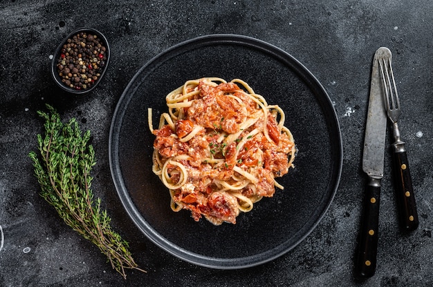 Pasta feta con tomates cherry al horno en un plato. Fondo negro. Vista superior.