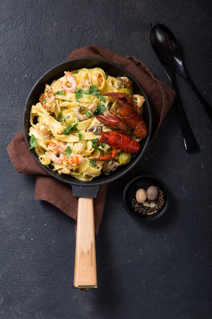 Pasta fettuccine de mariscos con langostinos, camarones de pulpo, en una sartén de piedra. Plato gourmet