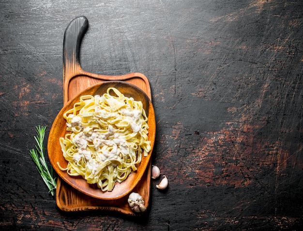 Foto pasta-fettuccine mit carbonara-sauce auf einem teller mit knoblauch und rosmarin