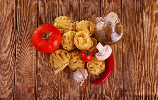 Pasta en el fondo de madera con tomate, pimiento, aceite de oliva, champiñones y lechuga