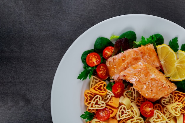 Pasta en forma de ensalada de corazón con salmón y verduras.