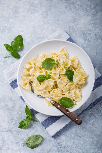 Pasta en forma de lazo rizado con albahaca sobre mesa de hormigón