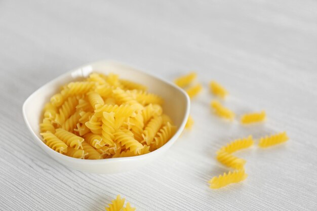 Pasta fresca sin cocer en un tazón en el primer plano de la mesa de madera