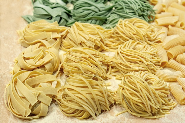 Pasta fresca cruda hecha en casa con espinacas y trigo en la mesa.