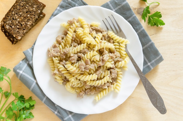 Pasta fusilli con carne picada en un plato blanco, vista superior.