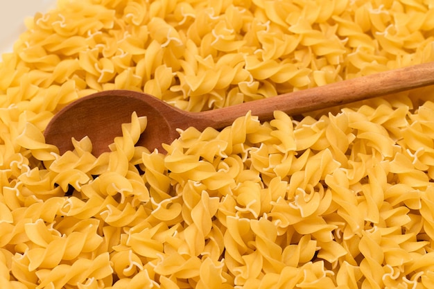 Pasta fusilli sin cocer con cuchara de madera