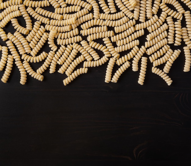 Pasta fusilli corti bucati sin cocer sobre fondo negro