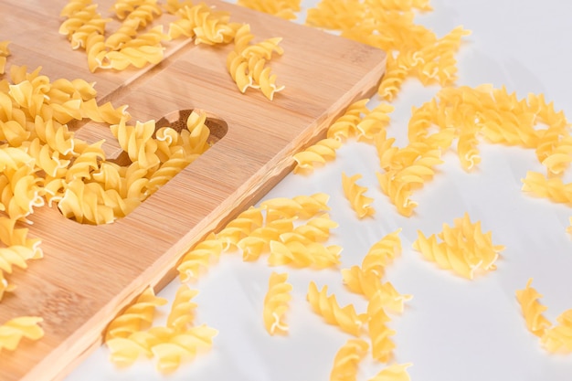 Pasta fusilli cruda esparcida sobre tablero de madera