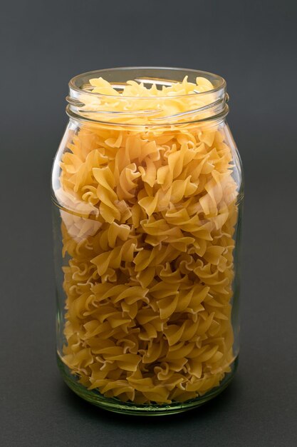 Pasta fusilli cruda en frasco de vidrio