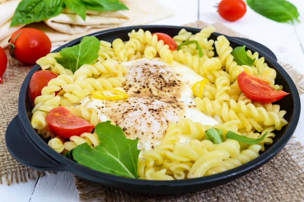 Pasta fusilli, huevos fritos y tomates en un plato