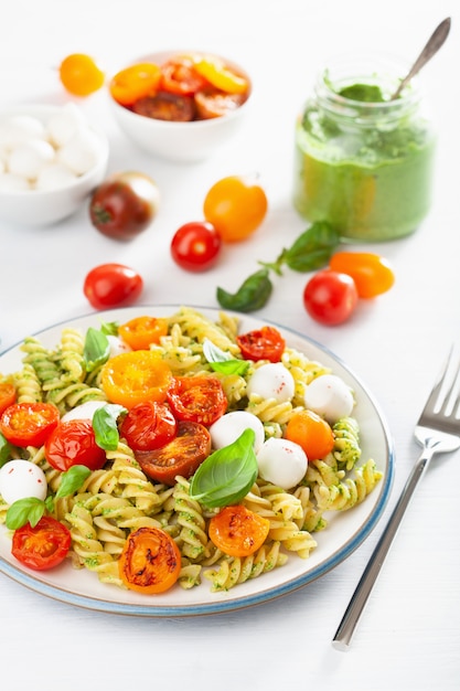 Pasta fusilli saludable con salsa de pesto, tomates asados, mozzarella