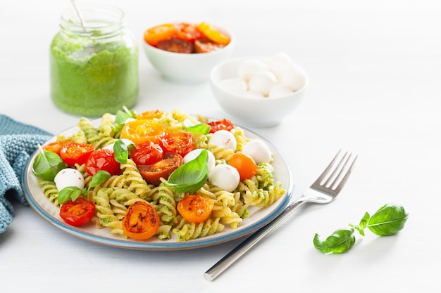 Pasta fusilli saludable con salsa de pesto, tomates asados, mozzarella