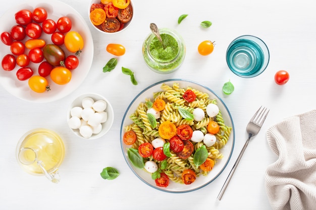 Pasta fusilli saludable con salsa de pesto, tomates asados, mozzarella