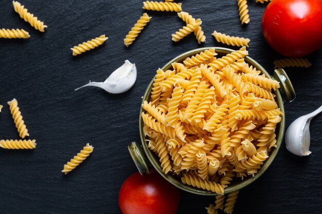 Pasta fusilli en un tazón de cerámica verde con ingredientes