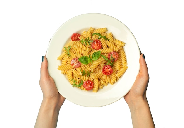 Foto pasta fusilli con tomates, hierbas y albahaca en un plato blanco aislado