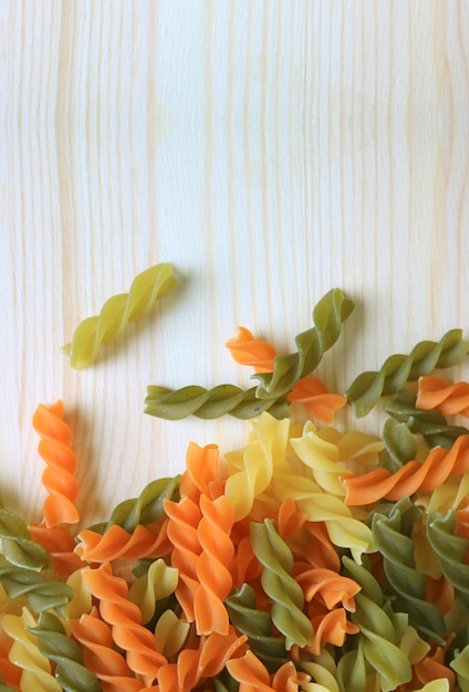 Pasta fusilli tricolor en mesa de madera