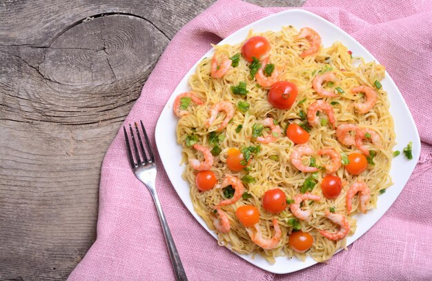 Foto pasta con gambas y tomate sobre fondo de madera