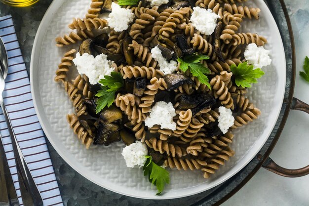 Foto pasta sin gluten de harina de farro de trigo medio con champiñones portobello y queso ricotta en una bandeja sobre una mesa de mármol recetas vegetarianas saludables