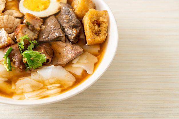 Pasta de harina de arroz o cuadrado de pasta china hervida con carne de cerdo en sopa marrón - estilo de comida asiática