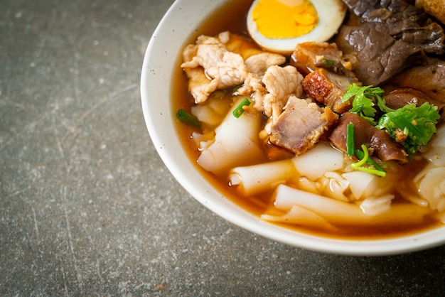 Pasta de harina de arroz o cuadrado de pasta china hervida con carne de cerdo en sopa marrón - estilo de comida asiática