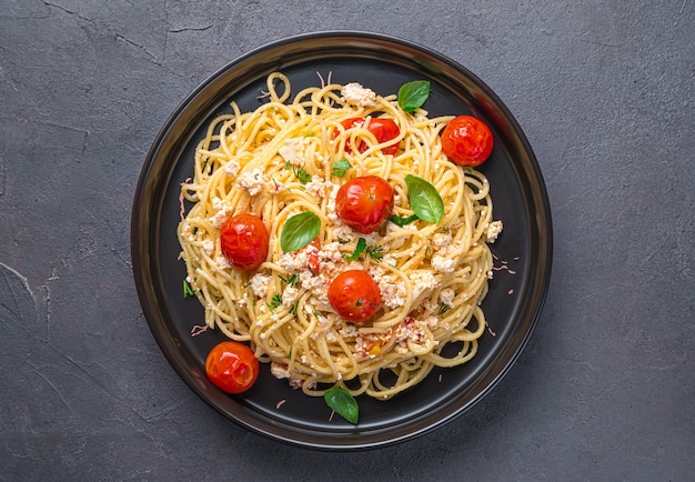 Pasta hecha de tomates con queso feta al horno y hierbas sobre un fondo oscuro Pasta feta vegetariana