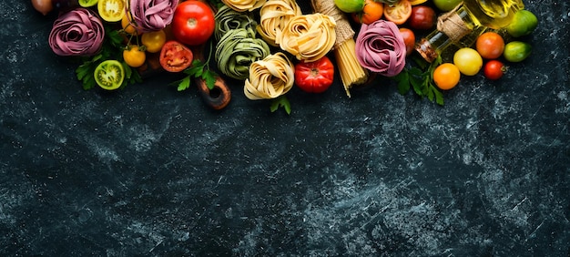 Pasta-Hintergrund Trockene Pasta Tagliatelle und Zutaten auf schwarzem Hintergrund Ansicht von oben Freier Platz für Ihren Text