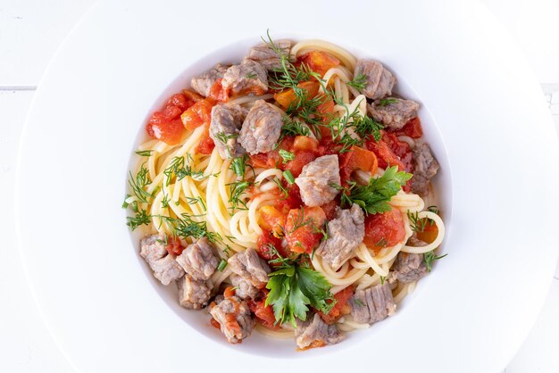 Pasta in Tomatensauce und Fleisch auf weißem Teller und weißem Hintergrund.