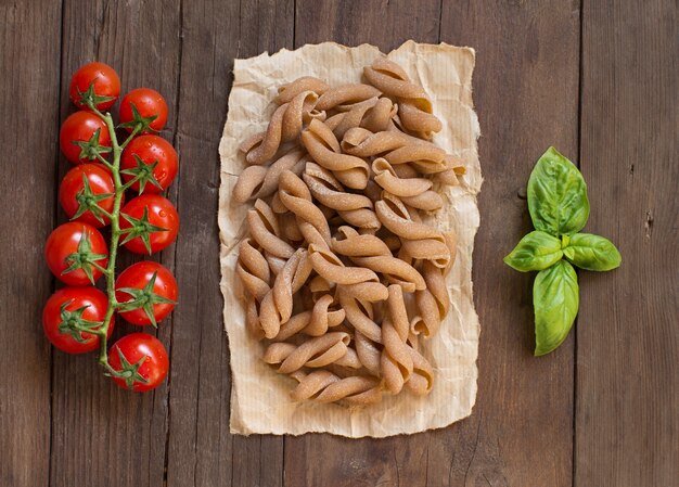 Pasta integral, tomate y albahaca sobre mesa de madera