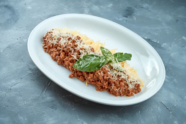 Pasta italiana casera - espaguetis a la boloñesa con salsa roja y carne picada en un plato blanco