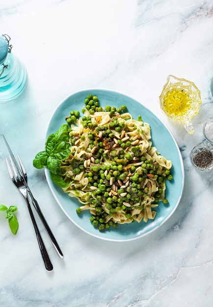 Foto pasta italiana casera de primavera con harina de garbanzos y pesto con guisantes frescos y piñones.