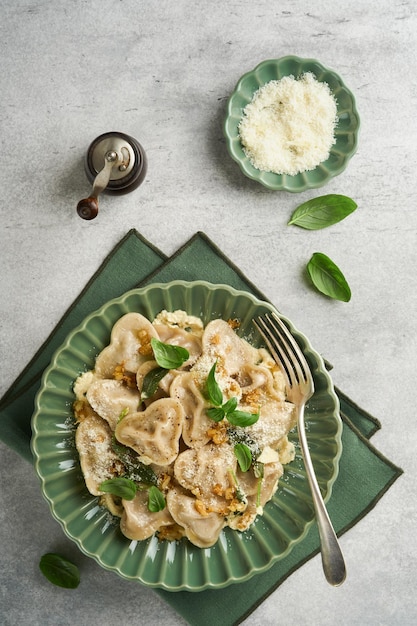 Pasta italiana casera de ravioli en forma de corazón con carne de res queso salsa de mantequilla cebollas caramelizadas albahaca y azafrán en un fondo gris viejo ingredientes del menú de cocina de alimentos fondo Vista superior