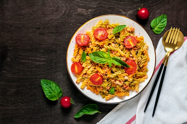 Pasta italiana clásica en salsa de tomate en un tazón blanco sobre la mesa de madera oscura.