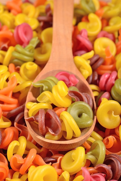 Pasta italiana de colores en una cuchara de madera